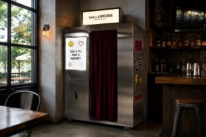 Classic photo booth vending machine installed against the wall of a bar next to the bottle shelves