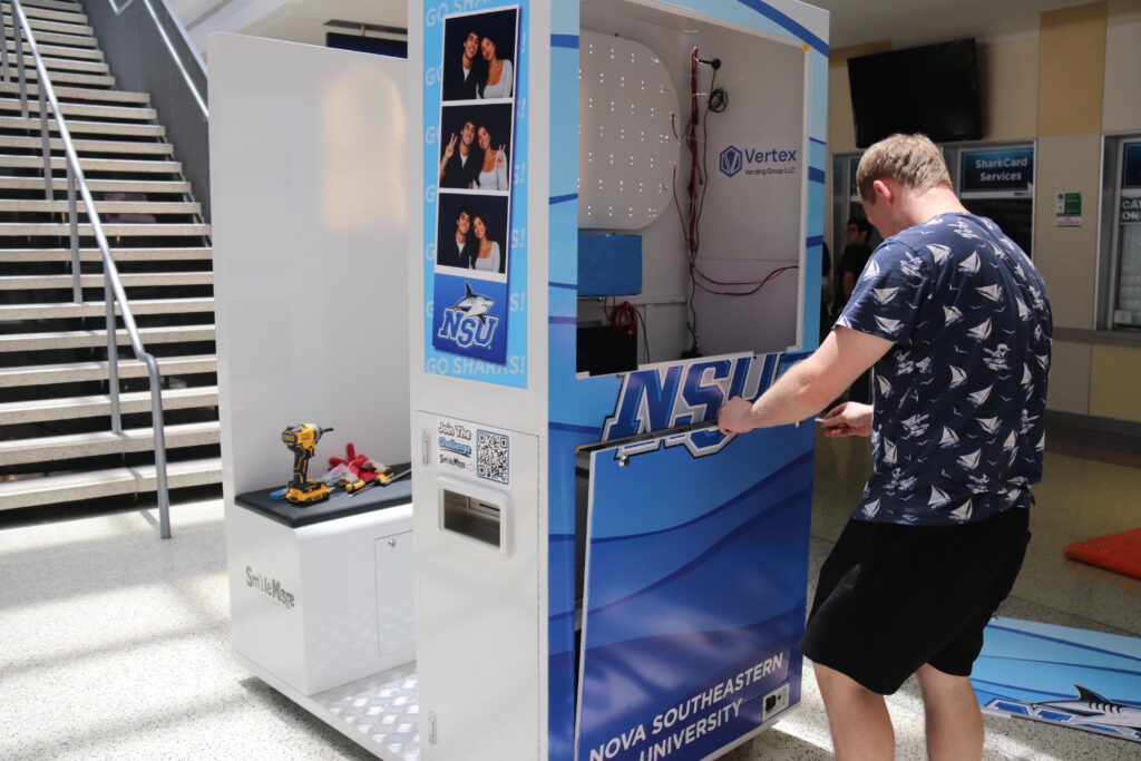 Two installers positioning the photo booth against the elevator column at NSU