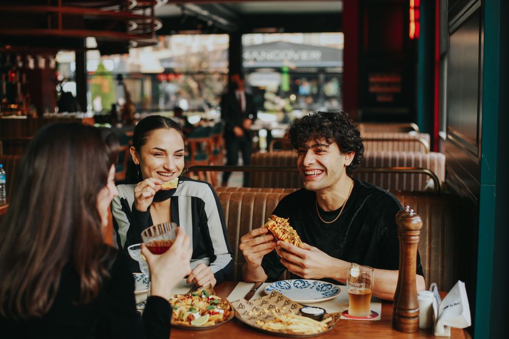 Group of friends laughing over a meal at a restaurant table