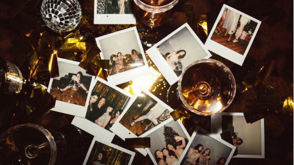 Photo booth strips scattered on a bar table after a party, with a disco ball and champagne glasses