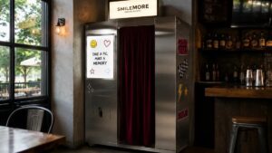 A SmileMore photo booth installed along the back wall of a bar, next to the bottle shelves