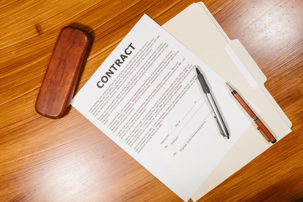 A printed contract and pen on a wooden desk