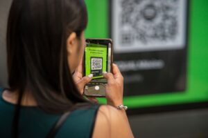 Woman scanning a QR code with her phone, the core of photobooth software with QR code sharing