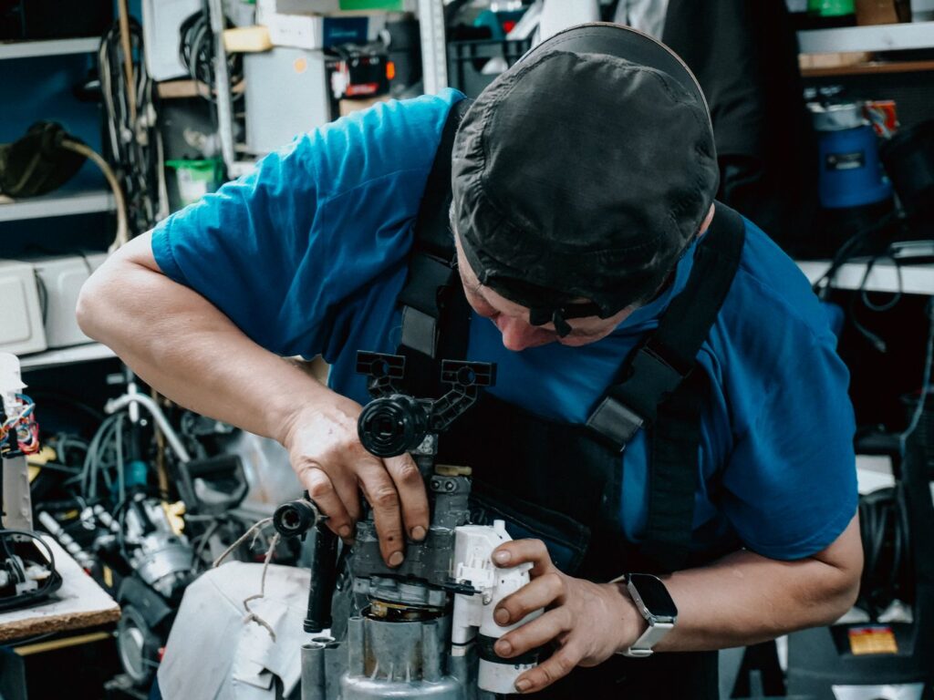 A technician repairing a machine at a workbench in a service workshop