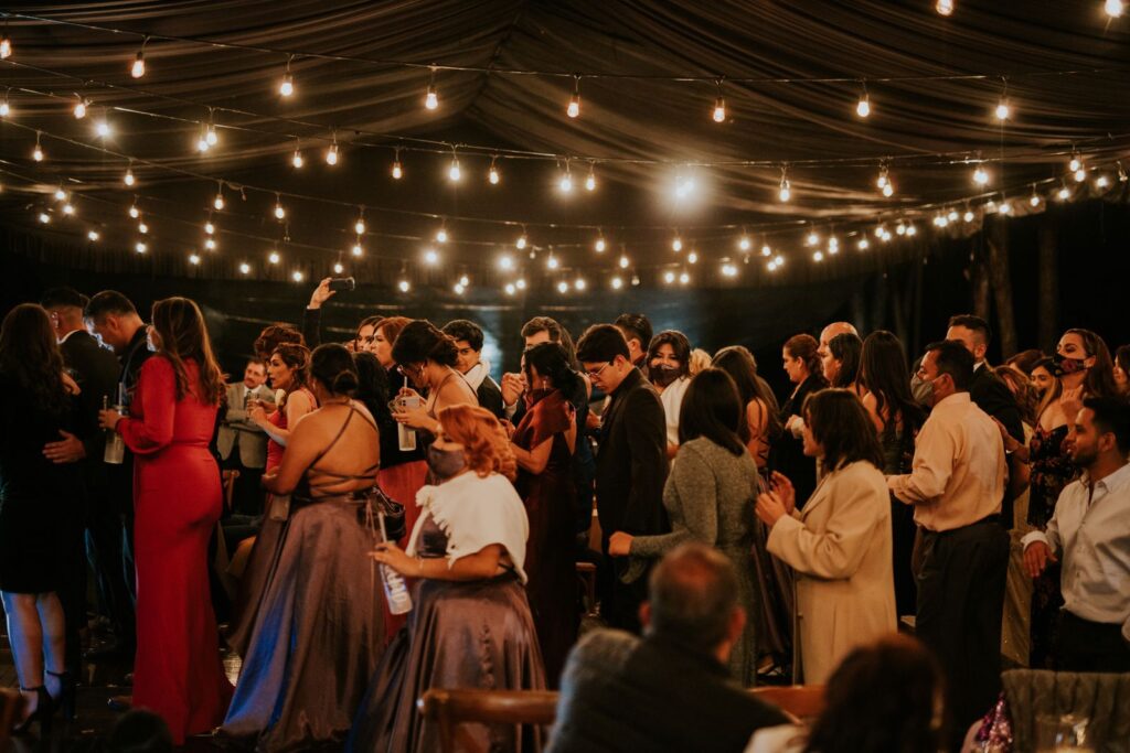 Wedding reception with guests under string lights, where a video guest book booth collects messages