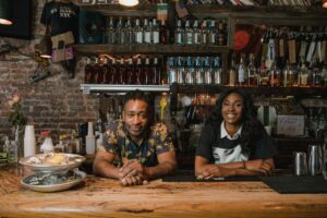 Two smiling bar owners behind their counter, the people who decide whether a vending machine goes in